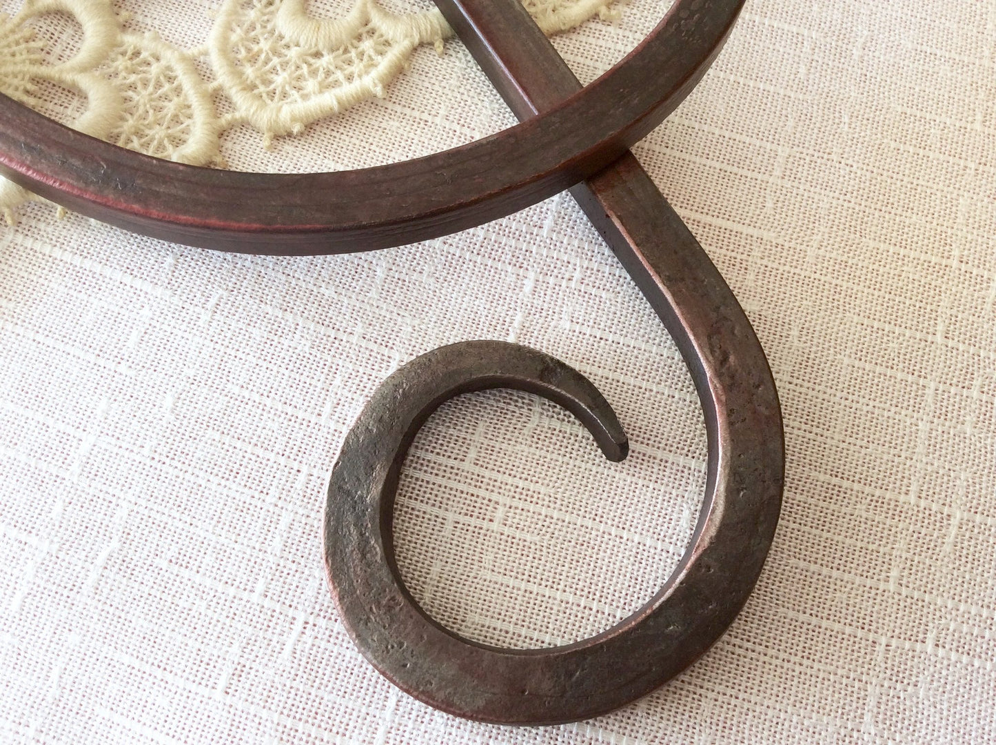 This tail of the forged iron treble clef shows the marks of the fire and hammer through the translucent red finish.